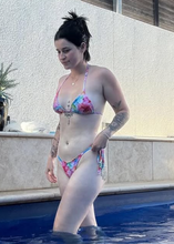 Load image into Gallery viewer, Woman in a colorful bikini standing by a pool with a plant and wall in the background