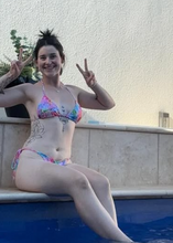 Load image into Gallery viewer, Woman in a colorful bikini sitting by a pool, making peace signs.