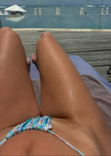 Load image into Gallery viewer, Close-up of a person wearing a colorful bikini bottom on a wooden deck with ocean view.