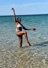 Load image into Gallery viewer, Person in a swimsuit standing in shallow water with a clear blue sky above.