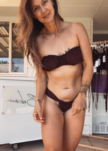 Load image into Gallery viewer, Woman wearing a brown bikini standing in front of a white vehicle with writing on it.