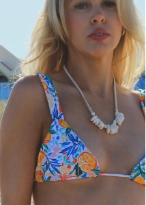 Woman wearing a colorful bikini with a tropical pattern on a beach.