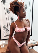 Load image into Gallery viewer, Woman wearing a pink leopard print bikini standing indoors with palm tree decorations.
