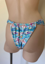 Load image into Gallery viewer, Blue swim bottoms with starfish and shell pattern on a mannequin against a plain background
