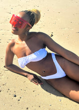 Load image into Gallery viewer, Person wearing a white bikini lying on a sandy beach
